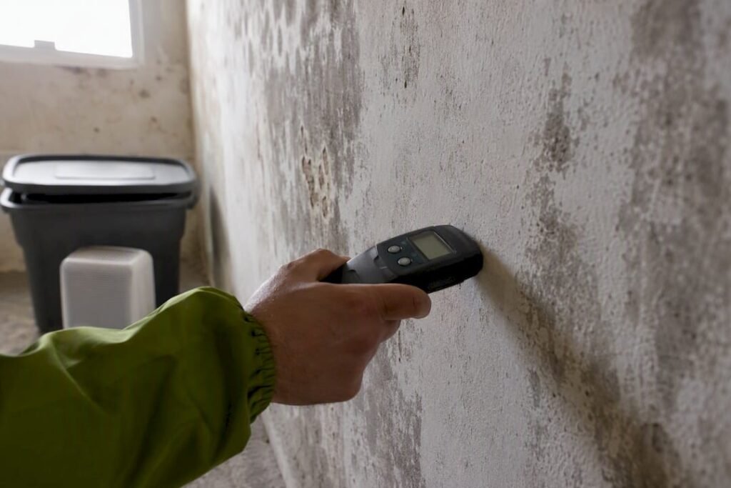 Medidor de humedad midiendo una pared húmeda en el cuarto de almacenamiento