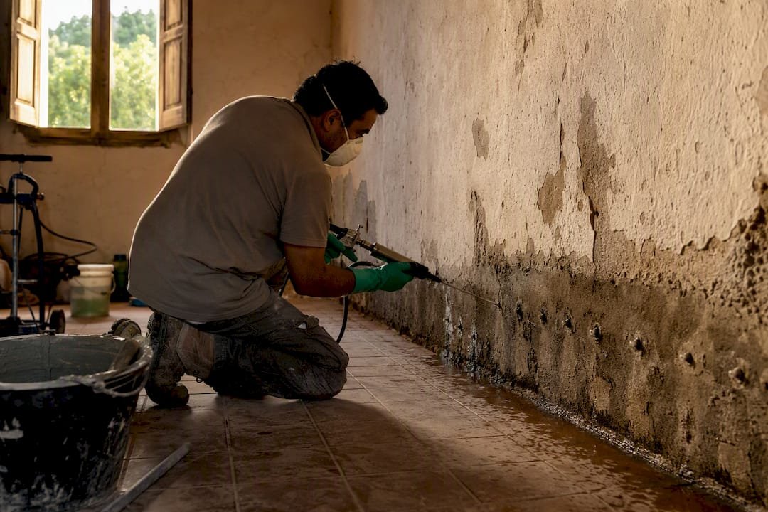 Técnico aplicando una barrera contra la humedad en un muro antiguo